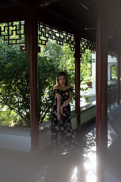 A young Chinese actor dressed in traditional costume, looking thoughtfully into the distance. The scene is set in a richly decorated historical courtyard.