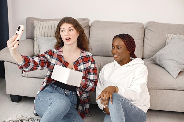 Two friends sitting on a couch, both holding smartphones and pointing at the screen while watching a Chinese drama. One friend is explaining a slang term to the other, creating a moment of shared learning and excitement.