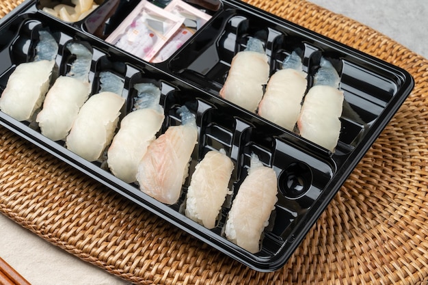 A neatly arranged bento box with compartments filled with Tamagoyaki (rolled omelette), Karaage (fried chicken), boiled broccoli, cherry tomatoes, and a small portion of white rice topped with sesame seeds.
