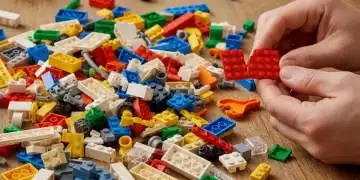 Hands inspecting a broken Lego brick among assorted colorful Lego pieces